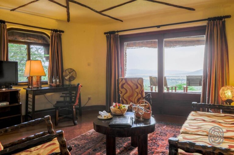 A seating area with a wooden coffee table, a fruit basket and a TV, in front of the French door to the balcony