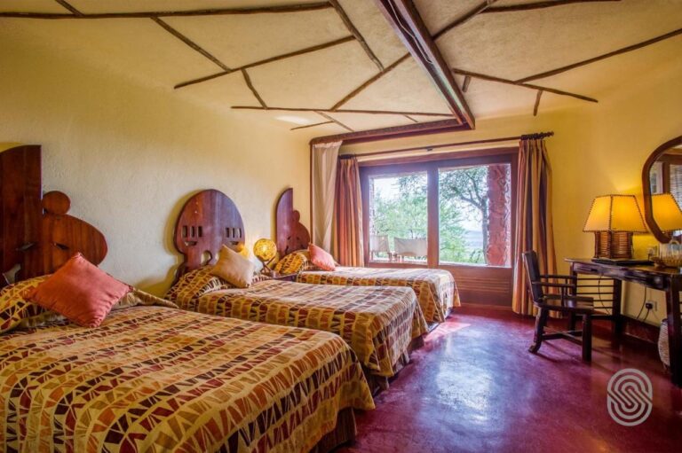 A room with three beds and carved wooden headboards, on a polished red floor