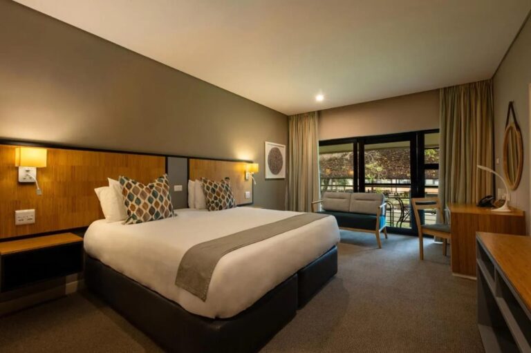 A room with a double bed, a sofa and a desk, opening onto a terrace