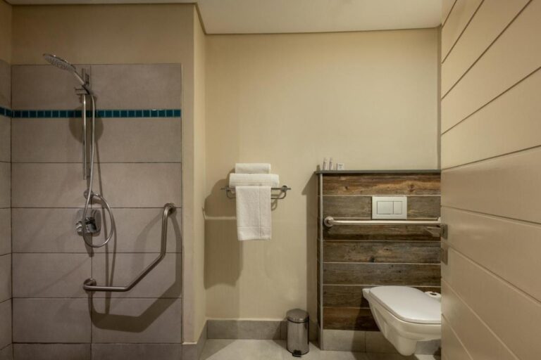 A bathroom with a step-free shower, grab bars and a wall-hung toilet