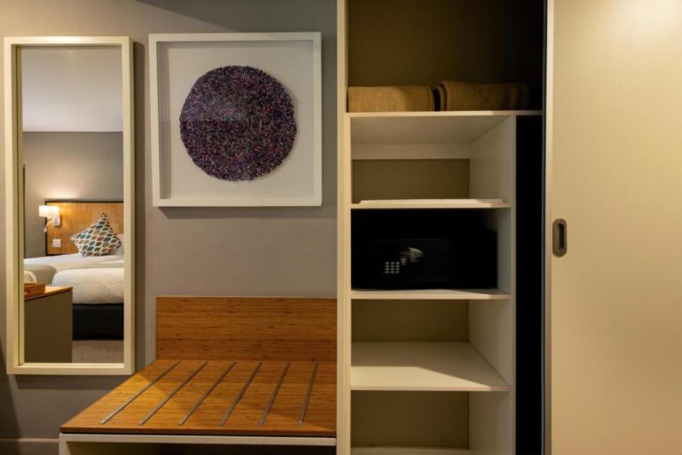 The storage area of a room, with shelves, a safe, a luggage rack and a mirror