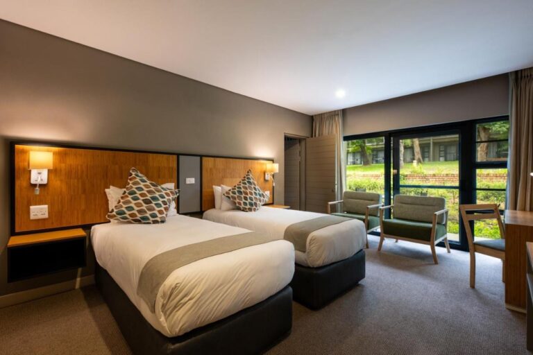 A room with two beds and two armchairs in front of the picture window