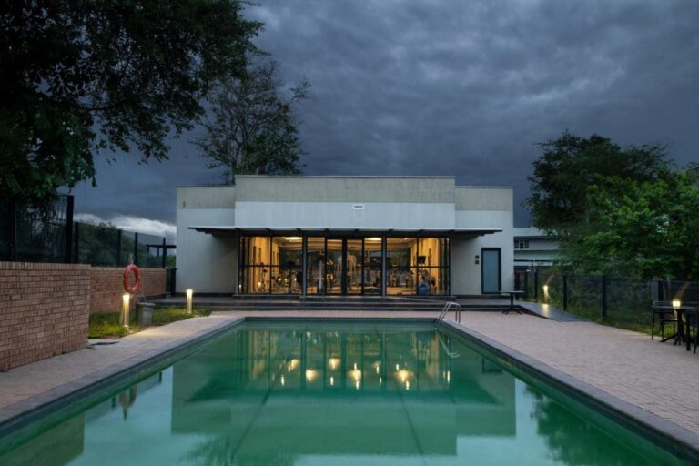 The outdoor pool in front of the glass-walled fitness room, under a stormy sky