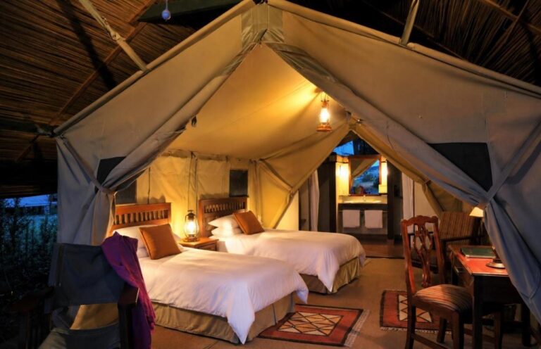 A twin tent under a thatched roof, lit by lanterns