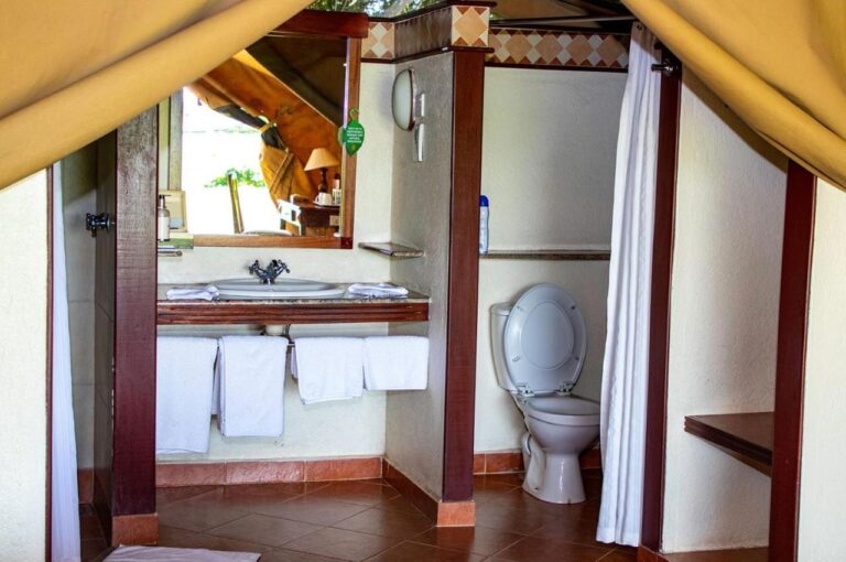 A tent's bathroom, with a sink, a toilet and a shower curtain