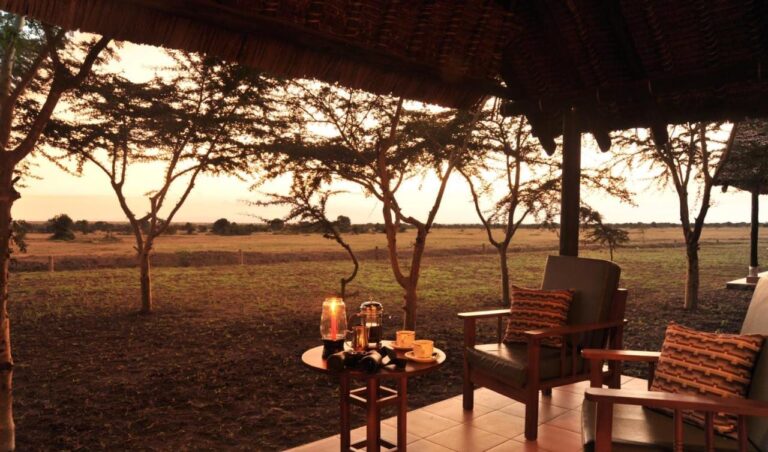 Two armchairs and a table with binoculars, a coffee pot and a lantern, facing the plain at dusk