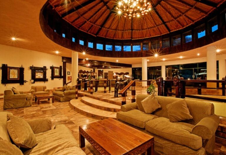 A circular lounge with sofas, under a wooden dome