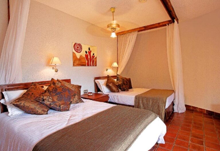 A room with two beds and African-print cushions