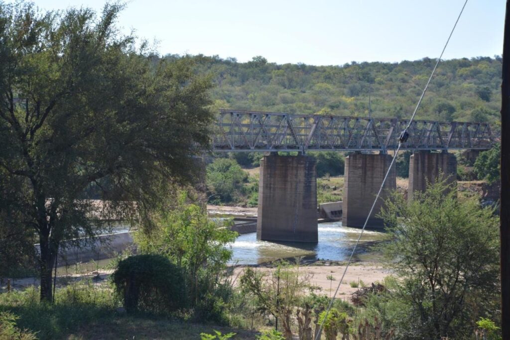 A steel bridge on concrete piers over the Olifants River, seen from the garden of Three Bridges B&B