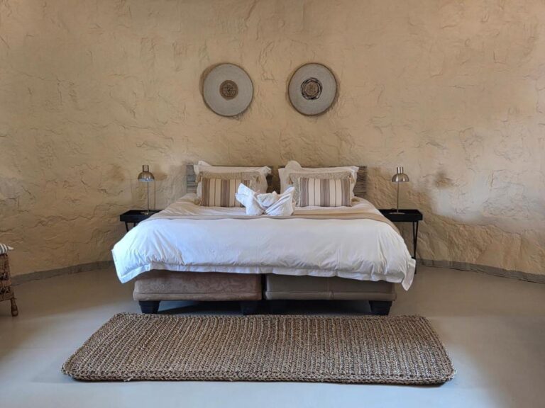 A double bed beneath two decorative discs, between two bedside lamps, with a woven rug