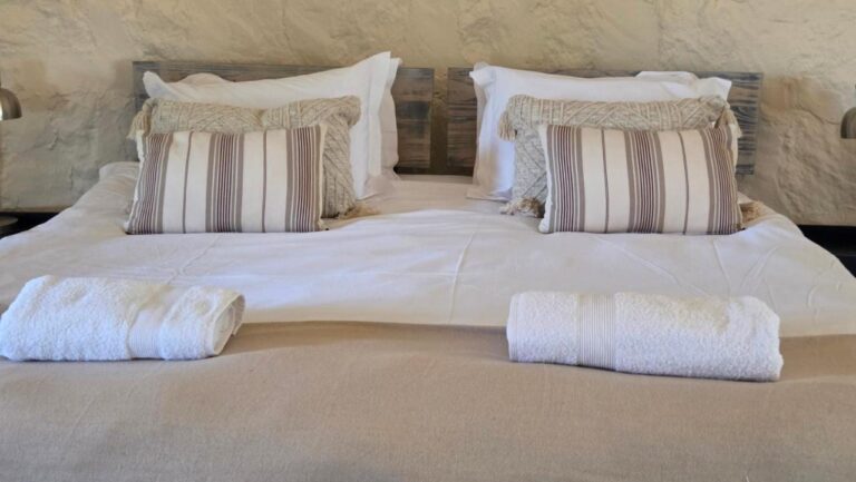 Striped cushions and folded towels on a white double bed