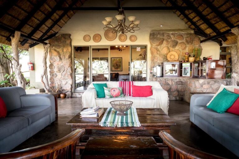 The open lounge of Umkumbe Safari Lodge, under the thatch, with gray sofas and stone walls