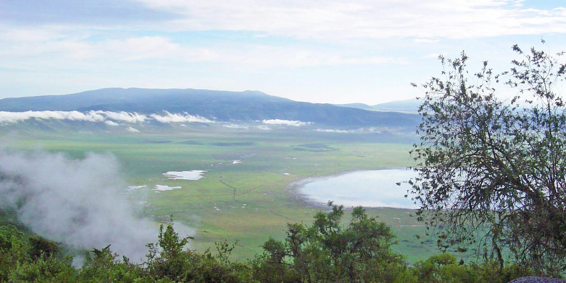 The green crater floor seen from the rim, with Lake Magadi and clouds clinging to the walls