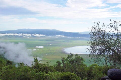 The green crater floor seen from the rim, with Lake Magadi and clouds clinging to the walls